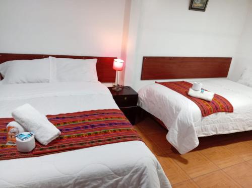 een hotelkamer met twee bedden en een lamp bij Casa Hospedaje Sunya in Cuzco