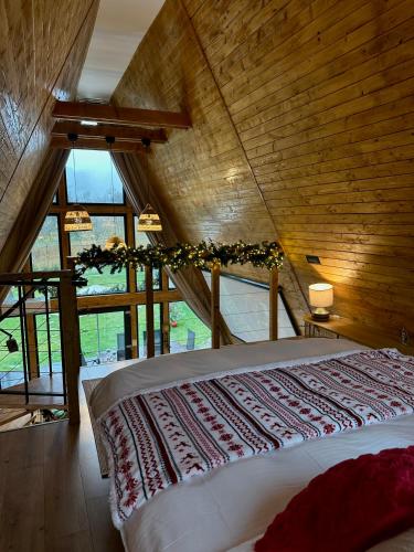 a bedroom with a bed in a room with windows at Cabana Zeneris in Vulcana de Sus