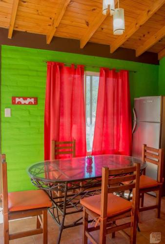 a dining room with a glass table and red curtains at Arcoiris de Cortaderas in Cortaderas