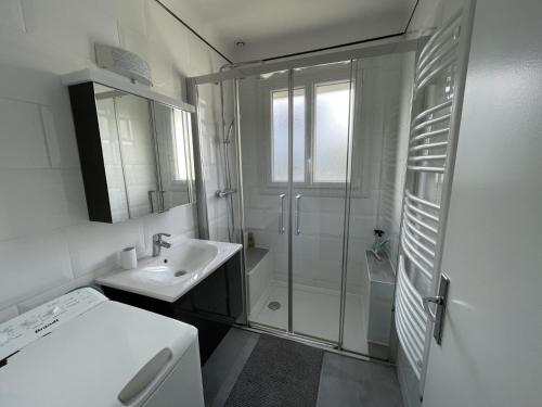 a white bathroom with a shower and a sink at Maison Dizavel in Le Croisic