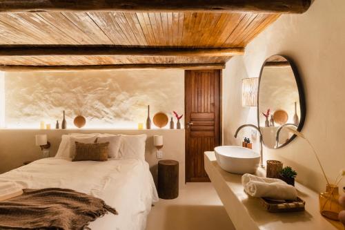 a bedroom with a bed and a tub and a sink at Mōmento Itamambuca in Ubatuba