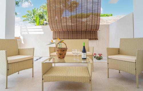 a table with two chairs and a bottle of wine at Cozy Apartment In Marzamemi With Swimming Pool in Marzamemi