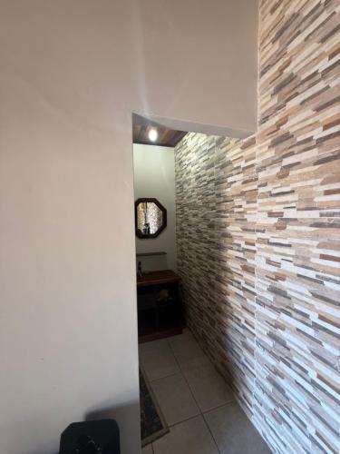 een hal met een bakstenen muur en een spiegel bij Casa com Espaço Gourmet e Piscina a 2min da Praia in Caraguatatuba