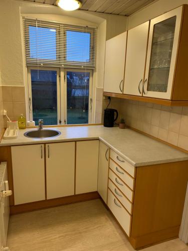 a kitchen with white cabinets and a sink and a window at Kiko in Horsens