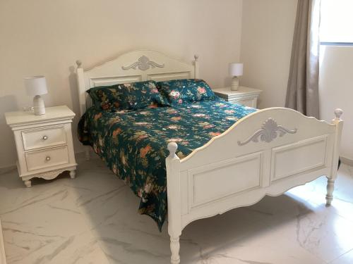 Malanda Falls Retreat في Malanda: غرفة نوم بسرير أبيض وطاولتين جانبيتين