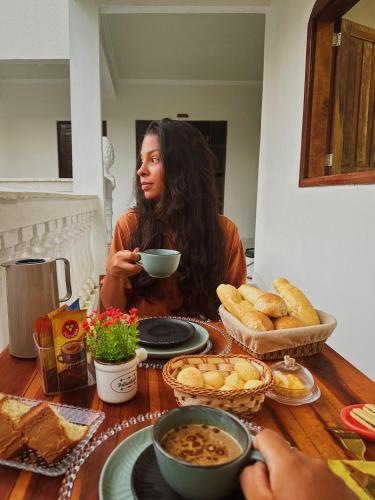 een vrouw aan een tafel met een kom eten bij Hotel Pousada Vila da Natureza in Maceió