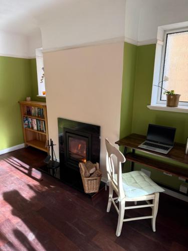 a living room with a fireplace and a laptop on a desk at Beach Bungalow in Bournemouth