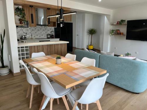 Moderno dpto de estreno en zona centrica في أريكيبا: مطبخ وغرفة طعام مع طاولة خشبية وكراسي بيضاء