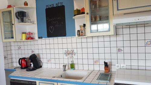 a kitchen with a sink and a white tiled wall at La choletaise spacieuse et proche des axes routiers in Cholet