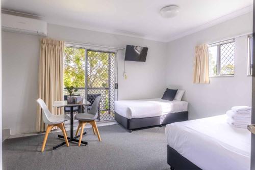 Un dormitorio con dos camas y una mesa y sillas. en Herston Place Motel, en Brisbane