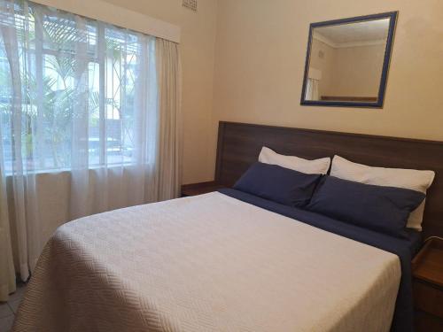 a bedroom with a bed with a mirror and a window at Cottage Sleeps 4 with Pool in Harare