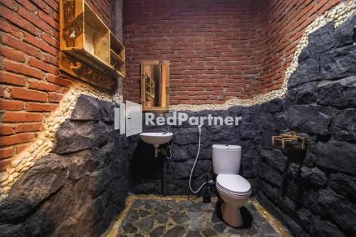 a bathroom with a toilet and a sink in a brick wall at Djawata Resort & Gallery near Desa Wisata Kasongan Yogyakarta RedPartner in Yogyakarta