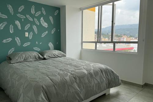 a bedroom with a bed with a green wall at Increíble Apartamento En Sogamoso in Sogamoso