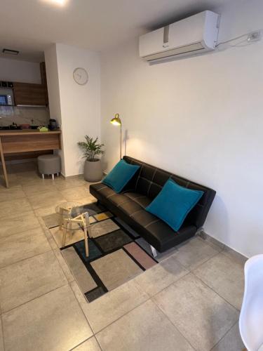 ein Wohnzimmer mit einem schwarzen Sofa und blauen Kissen in der Unterkunft Estilo City in San Francisco