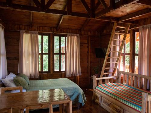 a bedroom with a bed and a ladder and windows at Cabañas El Coyote in San Pablo