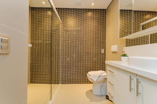 a bathroom with a toilet and a glass shower at Helbor Stay Batel in Curitiba