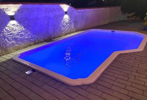 a blue swimming pool on a brick patio at night at Casa com PISCINA - 02 Quartos à 900m PRAIA e 3km do Beto Carrero - Estacionamento - Area de LAZER com Churrasqueira e SINUCA - Wi-Fi e Cozinha Completa in São Lídio