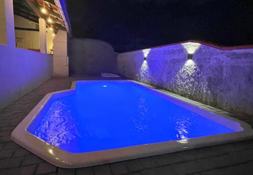 a blue swimming pool with a stone wall at Casa com PISCINA - 02 Quartos à 900m PRAIA e 3km do Beto Carrero - Estacionamento - Area de LAZER com Churrasqueira e SINUCA - Wi-Fi e Cozinha Completa in São Lídio