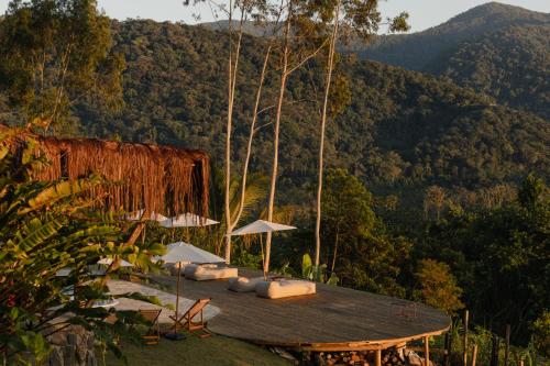 a deck with chairs and umbrellas on a mountain at Mōmento Itamambuca in Ubatuba