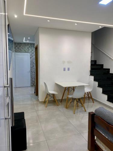 a room with a table and chairs and stairs at Seu Lar de Praia p Família e amigos 400m do Mar em Condomínio in Praia Grande
