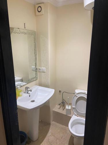a bathroom with a sink and a toilet and a mirror at Résidence TPM in Casablanca