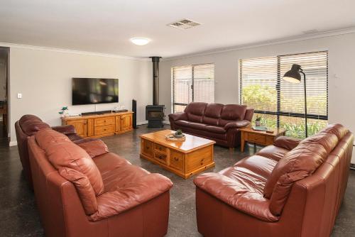 a living room with leather furniture and a flat screen tv at Busselton Broadwater Holiday Home in Busselton