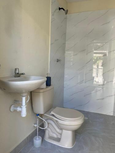 a bathroom with a white toilet and a sink at Casa Agarj in Santa Marta