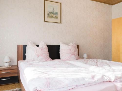 een slaapkamer met een wit bed met roze kussens bij Hehner 2 Comfortable holiday residence in Patersberg