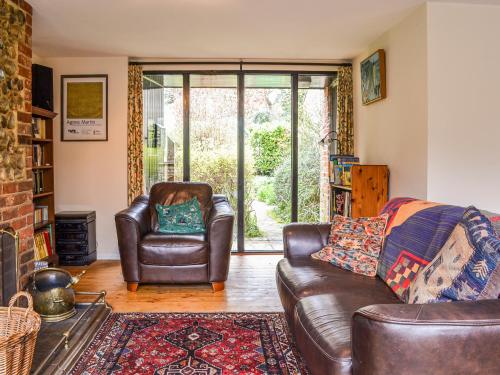 a living room with a leather couch and a chair at Owl Barn in Sidestrand