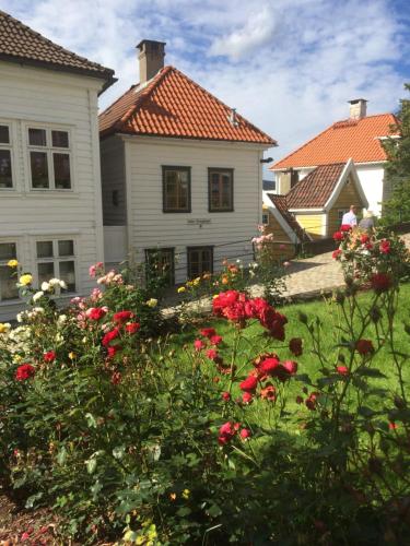una casa blanca con flores rojas en el patio en Annehelenes B&B en Bergen