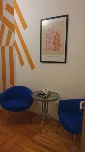 Dos sillas azules y una mesa con una taza encima. en Cozy rooms near the New York cafe, en Budapest