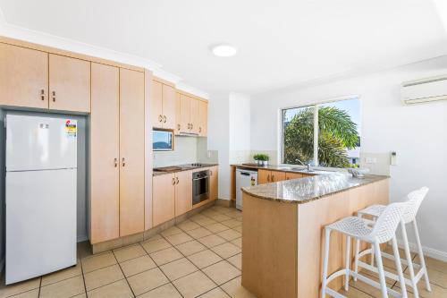 a kitchen with wooden cabinets and a white refrigerator at 'Villa Mar Colina U12' Coastal Escape, Yeppoon in Yeppoon