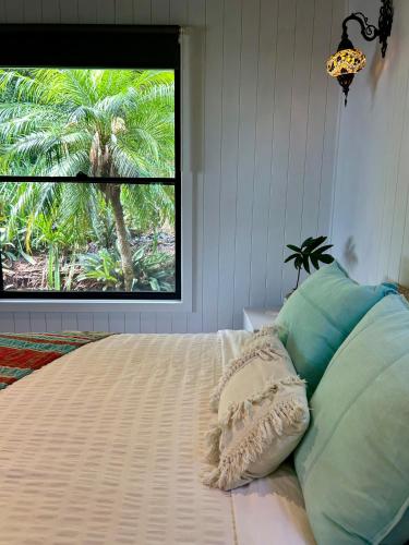a bedroom with a bed with a window with palm trees at Byron Bay Hinterland Sanctuary in Federal