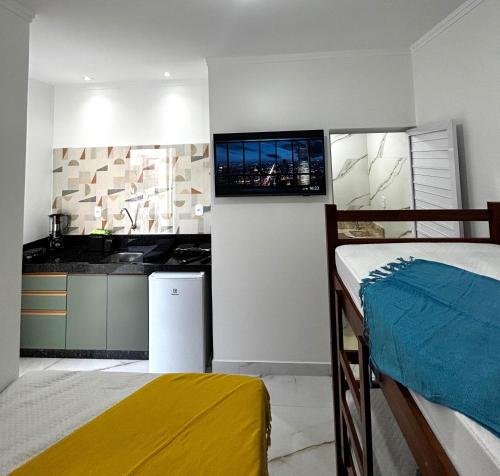 een kamer met een bed en een keuken met een televisie bij Aquarela Flats in Piranhas