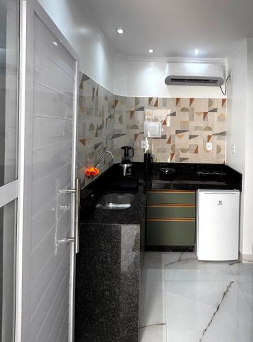 a small kitchen with a sink and a refrigerator at Aquarela Flats in Piranhas