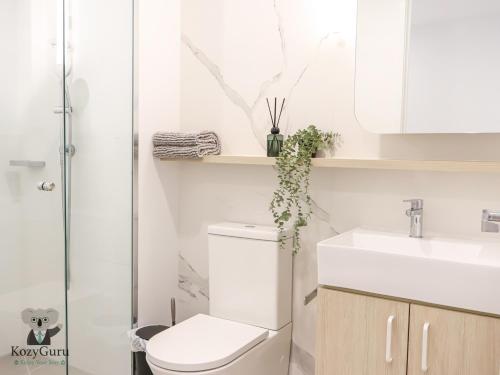 a bathroom with a toilet and a sink at KozyGuru | Box Hill | Elegant City Hideaway in Box Hill