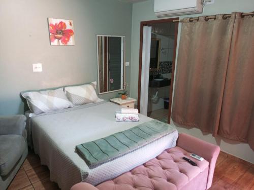 a bedroom with a bed and a pink ottoman at Studio Carimã Foz in Foz do Iguaçu