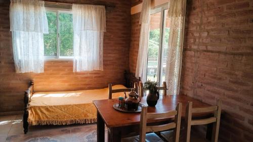a bedroom with a table and a bed with windows at Cabañas Las Pasionarias in Tanti