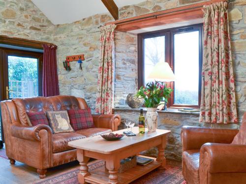 Campion Cottage في Saint Teath: غرفة معيشة مع أريكة جلدية وطاولة
