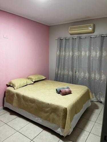 een slaapkamer met een bed en een roze muur bij Linda Casa com Piscina e Edícula Gourmet Ouro verde in Foz do Iguaçu