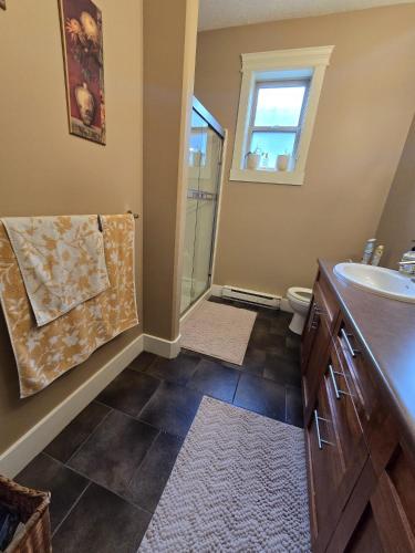 a bathroom with a sink and a toilet and a window at Bright Private Room in Echo Valley Home in Victoria