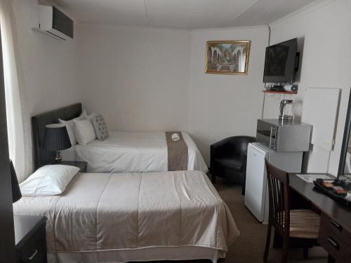 a hotel room with two beds and a desk at Moshitametsi Guesthouse in Kempton Park