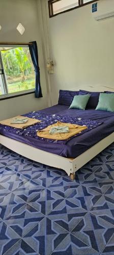 a bedroom with a bed with purple sheets and a window at Kohmook cocobeach in Ko Mook