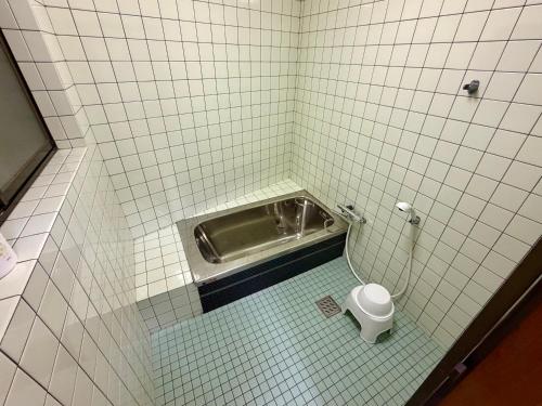 a tiled bathroom with a toilet in a stall at Nomad Kumano in Nachikatsuura
