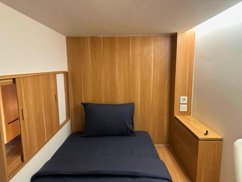 a small room with a bed and wooden walls at Althia Private Capsule Quarters in Badung