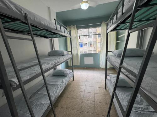 a room with three bunk beds and a window at 3 min da Praia de Copacabana - Apartamento Compartilhado PR in Rio de Janeiro