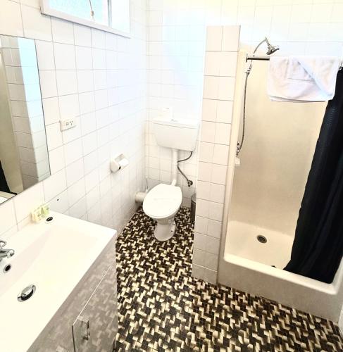 a bathroom with a toilet and a sink and a shower at Tartan Motel, Yea in Yea