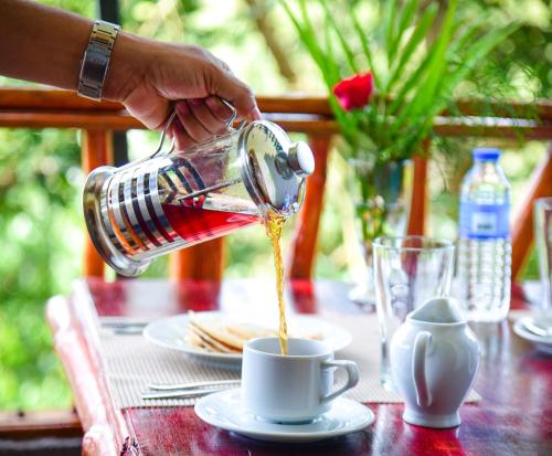 una persona che versa il caffè in una tazza su un tavolo di Mountain Face inn a Ella