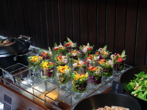 武漢市にあるAtour S Hotel Wuhan Mixc Xinhua Roadのガラス容器に入ったたくさんのサラダが並ぶビュッフェ