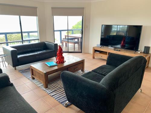 a living room with couches and a flat screen tv at Sandcastle - A Esplanade Place, Stunning Views in Kingscote